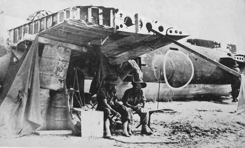 Australian Troops shelter under aircraft wing 