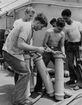 Crew of USS John W Thomason (DD-760) emptying shell cases 